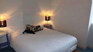 A neatly made bed with a white duvet and a patterned pillow, flanked by two wall-mounted lamps with patterned shades. - La Bonnerie - The Dream Observatory (La Bouëxière)