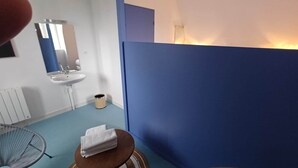 A bathroom with a blue partition, a sink, a mirror, a trash bin, and a fan. - La Bonnerie - The Dream Observatory (La Bouëxière)