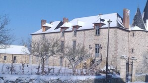 Un edificio de piedra con varias chimeneas y un tejado cubierto de nieve.