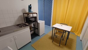 Cocina compacta con estufa, refrigerador y una pequeña mesa con sillas.