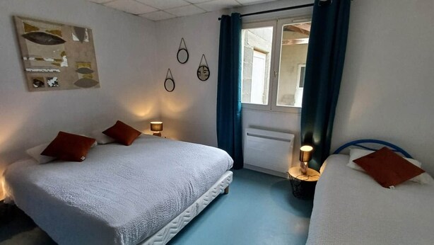 Una habitación de hotel con una cama grande, dos mesitas de noche, una ventana con cortinas y decoración en la pared.