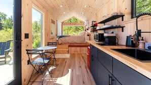 A compact wooden cabin with a kitchenette, a dining area, and a bed.