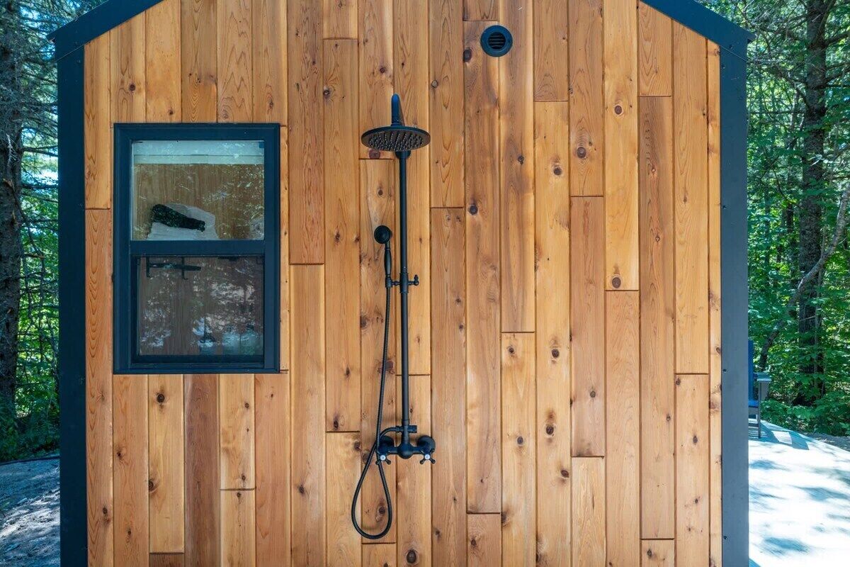 Une cabane en bois avec une douche, une fenêtre et une porte.
