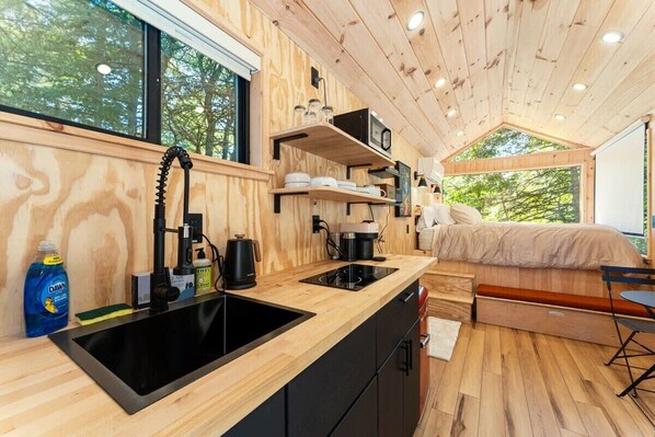 A compact, modern cabin with a kitchenette, a bed, and a dining area.