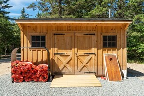 A wooden cabin with two doors, a window on each side, and a ramp leading to the entrance.