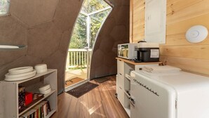 Une cuisine de taille réduite, avec un réfrigérateur blanc, une machine à café et un plan de travail en bois.