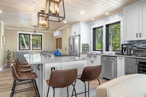A modern kitchen with a large island, stainless steel appliances, and a view of the outdoors.