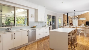 A modern kitchen with white cabinetry, a central island, and large windows.