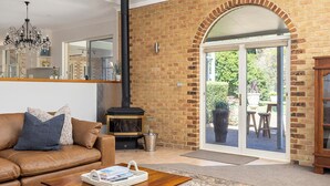 A cozy living room with a leather sofa, a fireplace, and a large glass door leading to an outdoor area.