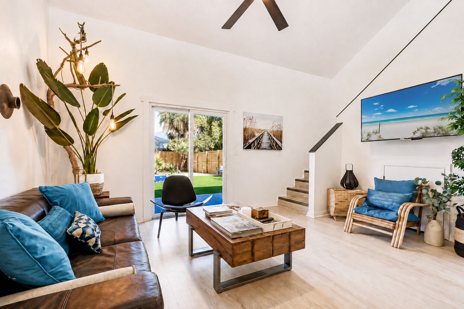 Un salon moderne avec un canapé en cuir, une table basse et une vue sur le jardin à travers des portes vitrées.