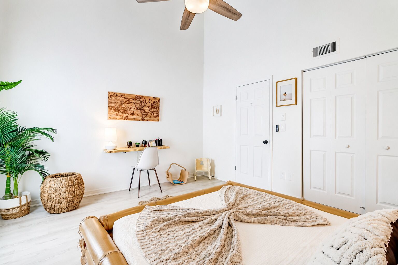 Une chambre à coucher comprenant un lit, un bureau, une chaise, une armoire et un ventilateur de plafond.