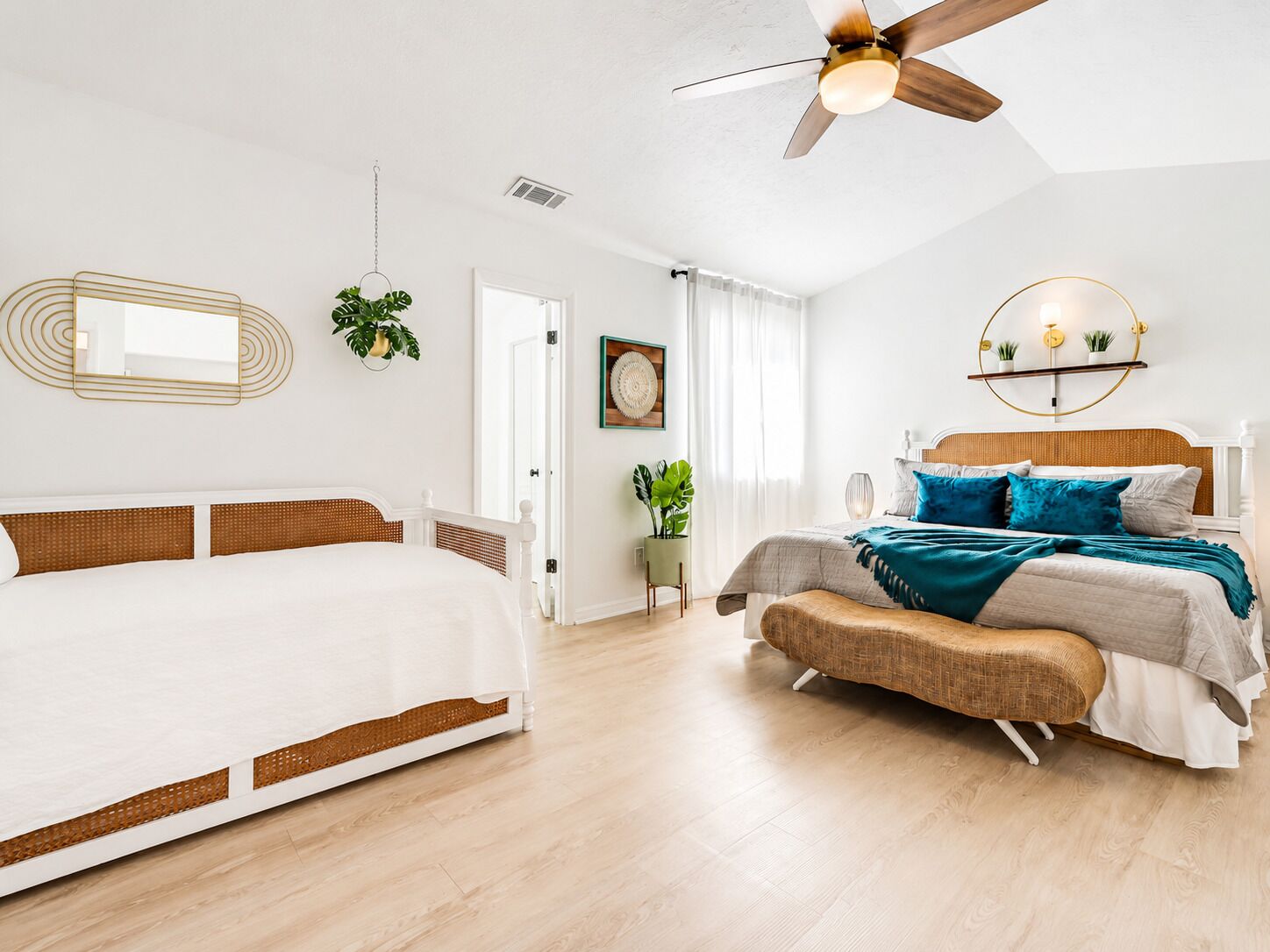A bedroom with a bed, a bedside table, a ceiling fan, and a wall-mounted shelf with plants.