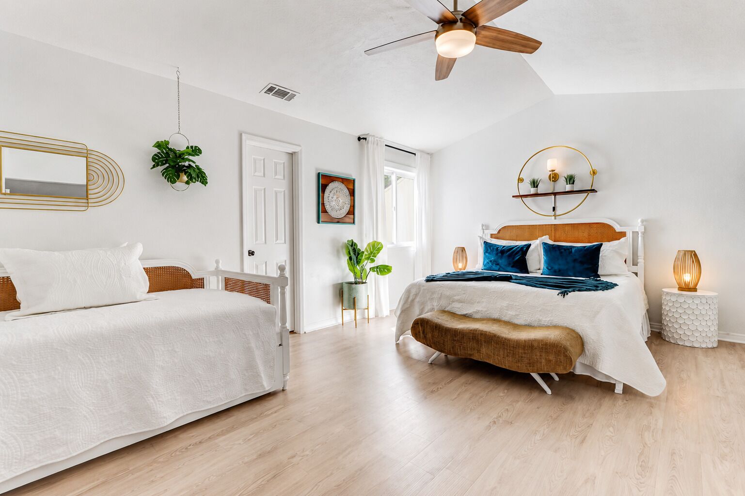 A bedroom with a bed, a ceiling fan, a bedside table, and a wall-mounted mirror.