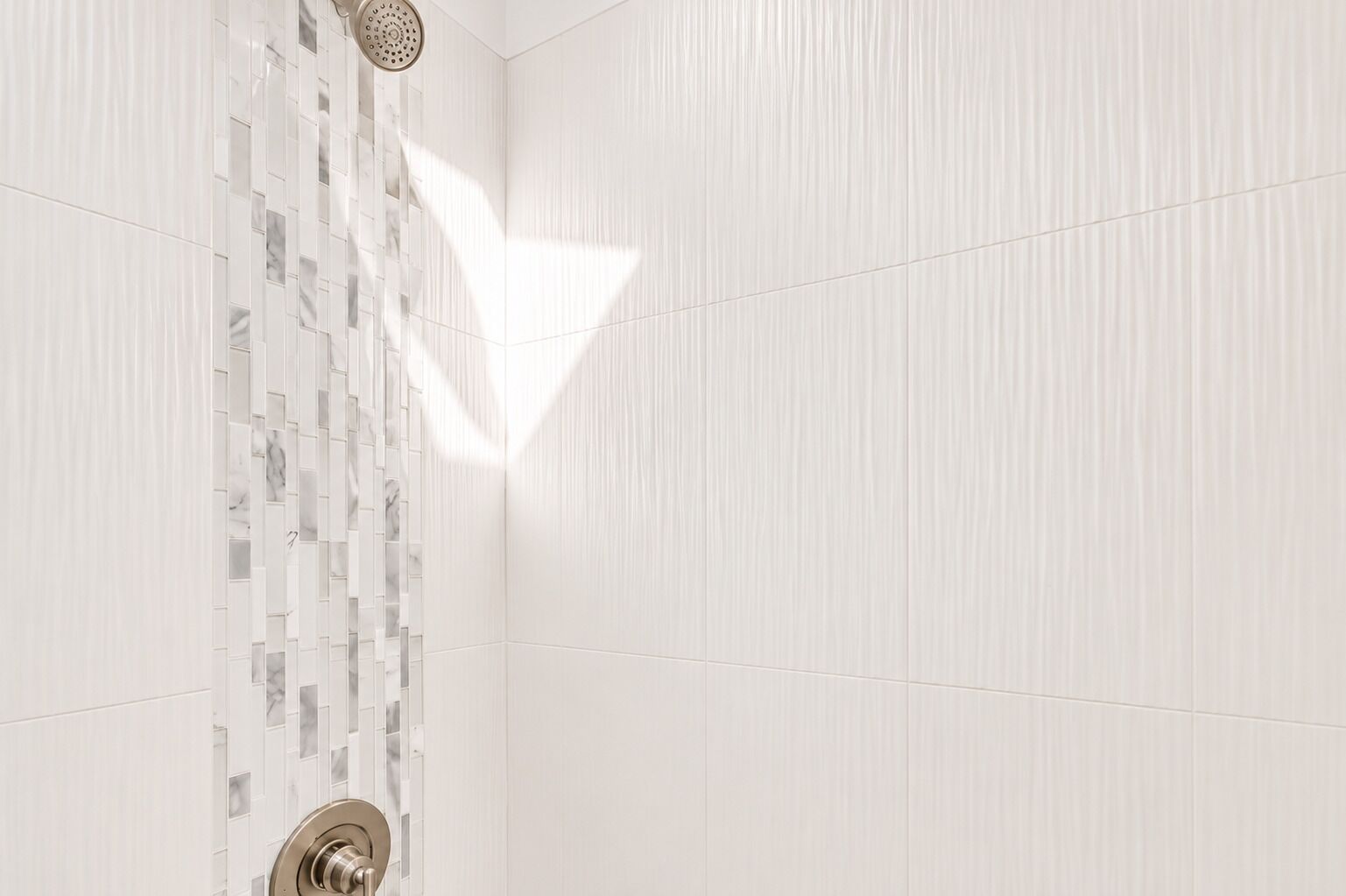 Une salle de bain avec un espace douche, des murs carrelés et un pommeau de douche.