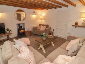 A cozy living room with a fireplace, sofas, a coffee table, and a television. - Pentwyn (Haverfordwest)