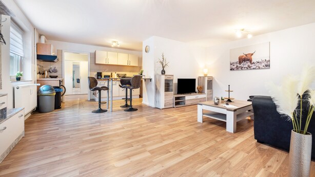 A modern living room with a TV, seating, and a dining area with a table and chairs. - Apartment 'Zum Waldblick' with Shared Garden and Wi-Fi (Wulsbüttel )