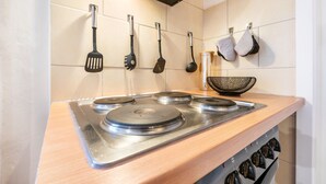 A kitchen with a stainless steel stove, hanging kitchen utensils, and a wooden countertop. - Apartment 'Zum Waldblick' with Shared Garden and Wi-Fi (Wulsbüttel )