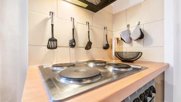 Une cuisine équipée d’une cuisinière en acier inoxydable, d’ustensiles de cuisine suspendus et d’un plan de travail en bois.
