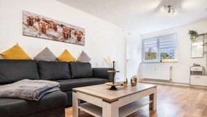A modern living room with a sofa, coffee table, and artwork on the wall. - Apartment 'Zum Waldblick' with Shared Garden and Wi-Fi (Wulsbüttel )
