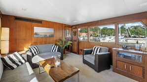 Un interior moderno con un juego de sofá, una mesa de centro de madera y vistas a la marina a través de amplios ventanales.