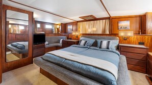Un dormitorio con una cama grande, televisión, paneles de madera y un espejo.