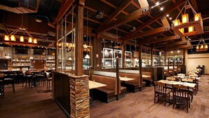Un restaurante con vigas de madera, pilares de piedra y varias zonas de estar, incluyendo cabinas y mesas.