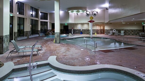 Una gran piscina interior con múltiples carriles, sillas de descanso y una fuente central.