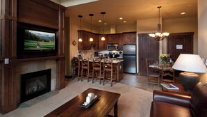 Una cocina moderna con armarios de madera, una isla central y un comedor con candelabro.
