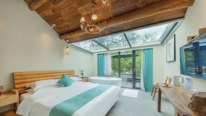 A bedroom with a wooden ceiling, a bed with white bedding and a teal throw, a round table, and a large window with curtains. - Anji Double Fish Hall Hot Spring Resort B&B (Longwangshan Canyon Drift Shop) (Anji)