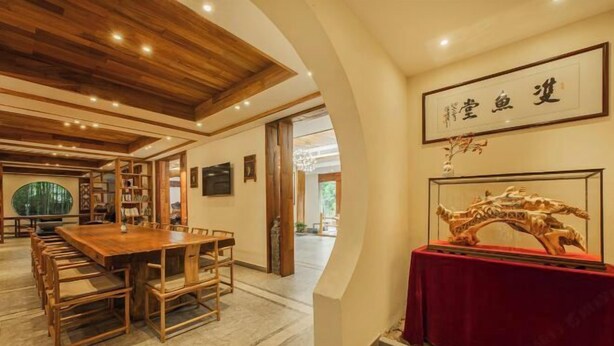A spacious room with a wooden dining table and chairs, a red-clothed display case, and a framed artwork on the wall. - Anji Double Fish Hall Hot Spring Resort B&B (Longwangshan Canyon Drift Shop) (Anji)