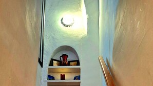 A staircase with patterned tiles, a wooden handrail, and a light fixture.