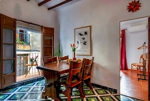 Un comedor con una mesa y sillas de madera, una planta en maceta y una obra de arte enmarcada en la pared.
