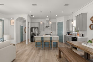 A modern kitchen with a central island, bar stools, and pendant lighting.