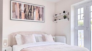Une chambre à coucher comprenant un lit, une table de chevet et une étagère fixée au mur, sur laquelle est posée une plante.
