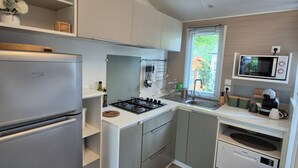 Une cuisine de taille réduite équipée d’un réfrigérateur, d’une cuisinière, d’un four à micro-ondes et d’un évier.