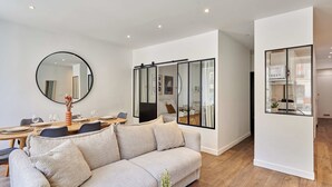 Una sala moderna con un sofá, una mesa de comedor para cuatro personas y un espejo grande.
