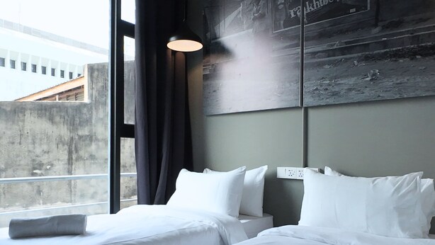 A hotel room with two beds, a large window, and a wall-mounted light fixture. - Rucksack Inn Premium Melaka (Malacca City)