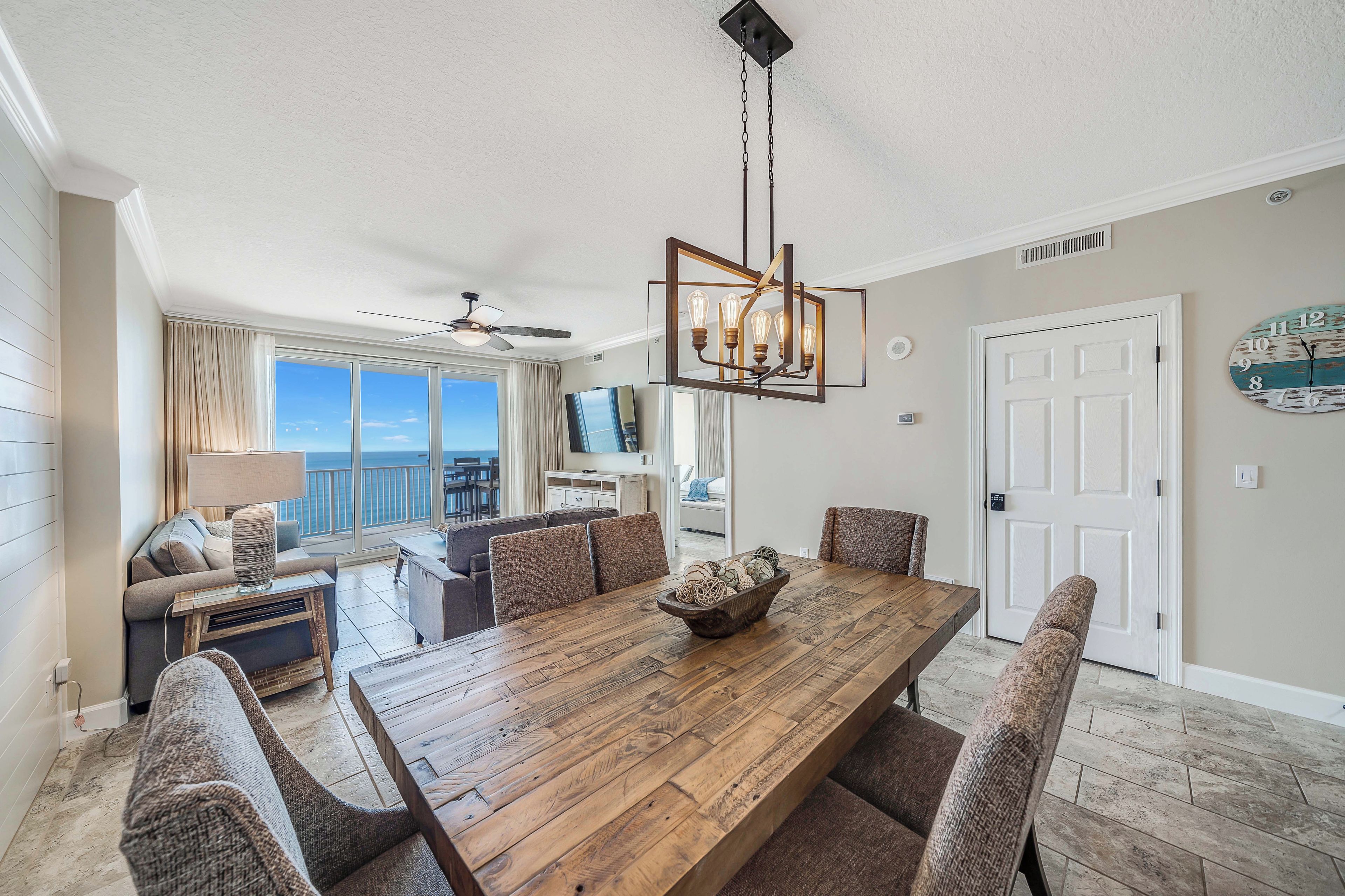 A spacious dining area with a wooden table, cushioned chairs, and a chandelier.