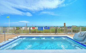 A pool with a view of the ocean, surrounded by a fence with various signs.