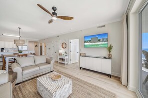 Een moderne woonkamer met een bank, bijzettafeltje en een televisie aan de muur.