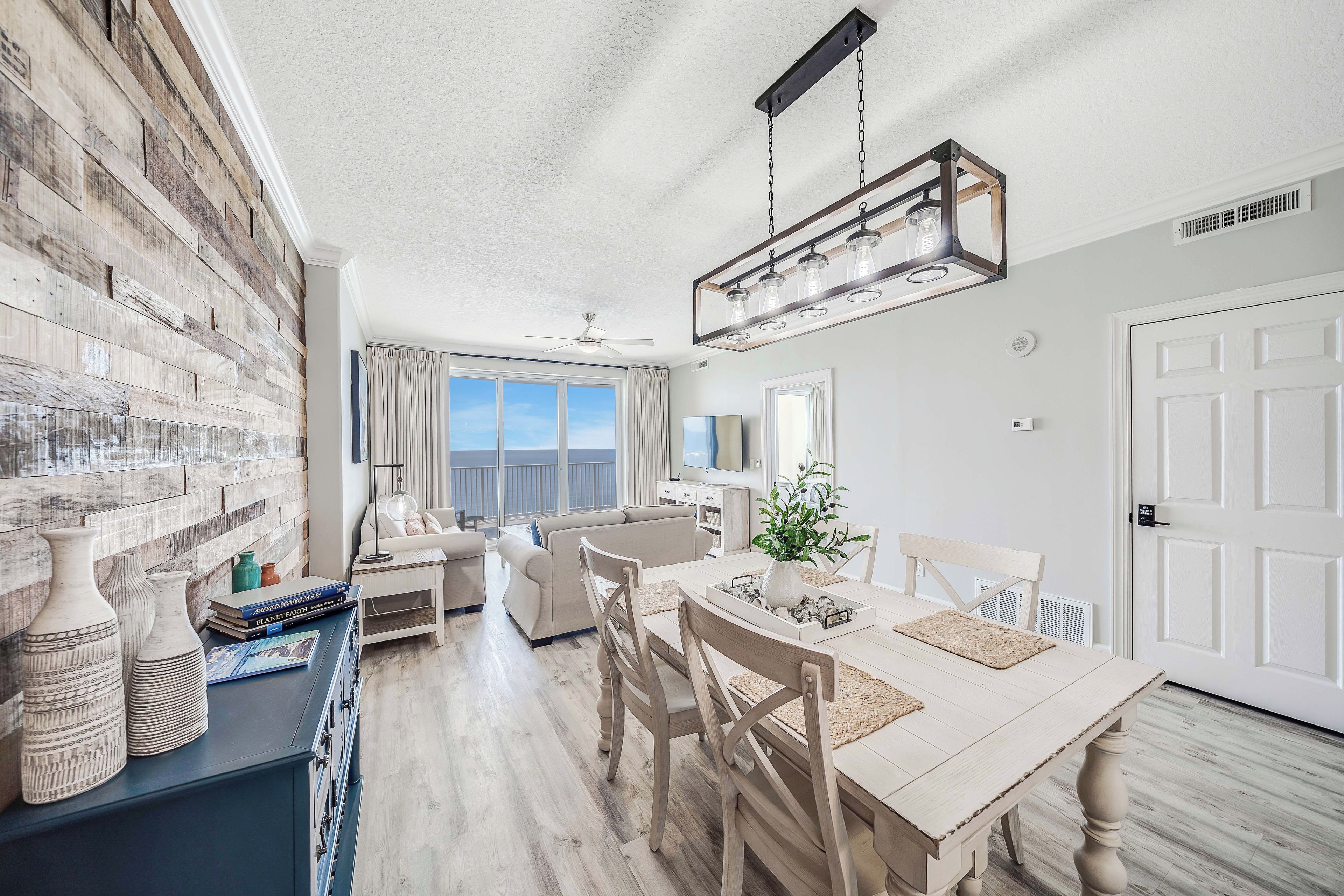 A modern living room with a large window, a dining area with a wooden table, and a built-in brick wall.