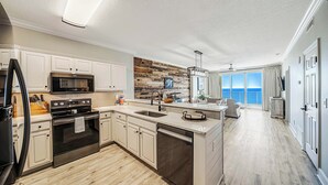 A modern kitchen with white cabinetry, stainless steel appliances, and a wooden backsplash. - NEW Emerald Isle 2107 "Manta Ray Villa" Pool, FREE Perks&Beach Service for 4! (Panama City Beach)