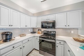 A modern kitchen with white cabinetry, a built-in microwave, and a stainless steel stove.