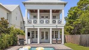 A two-story house with a balcony, a pool, and a wooden deck.