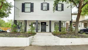 A two-story house with a front porch, a front door, and a small garden area.