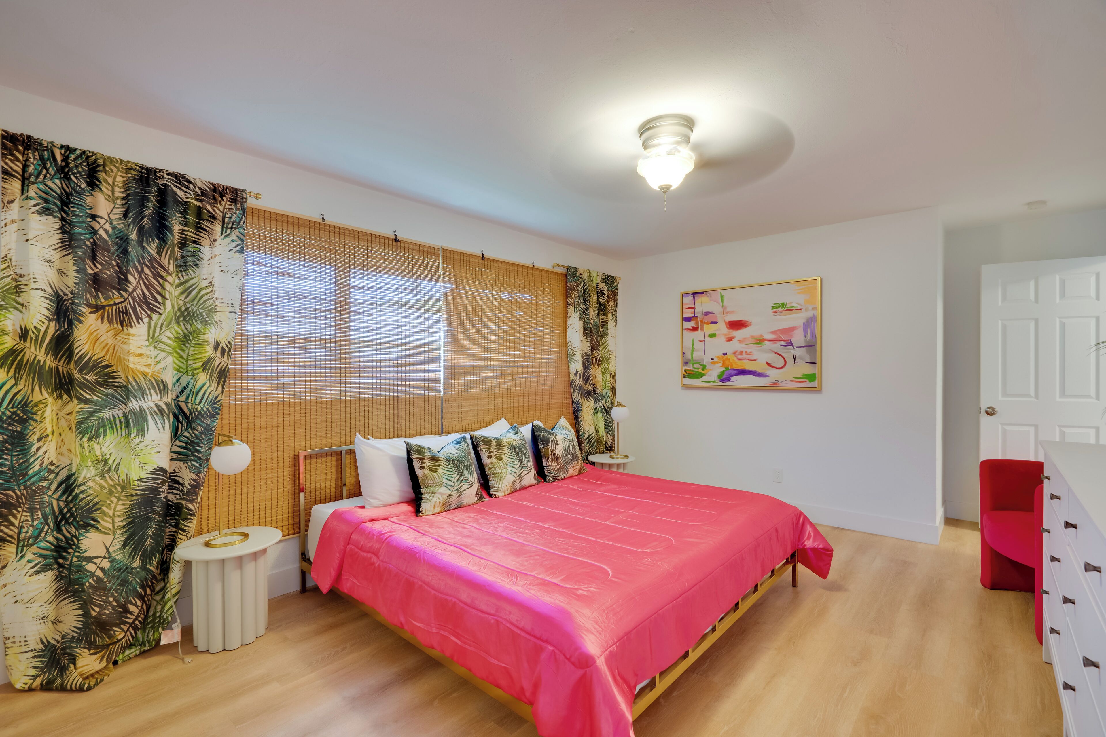 Ein Schlafzimmer mit Bett, Vorhängen, Nachttisch, Lampe und einer Tür.