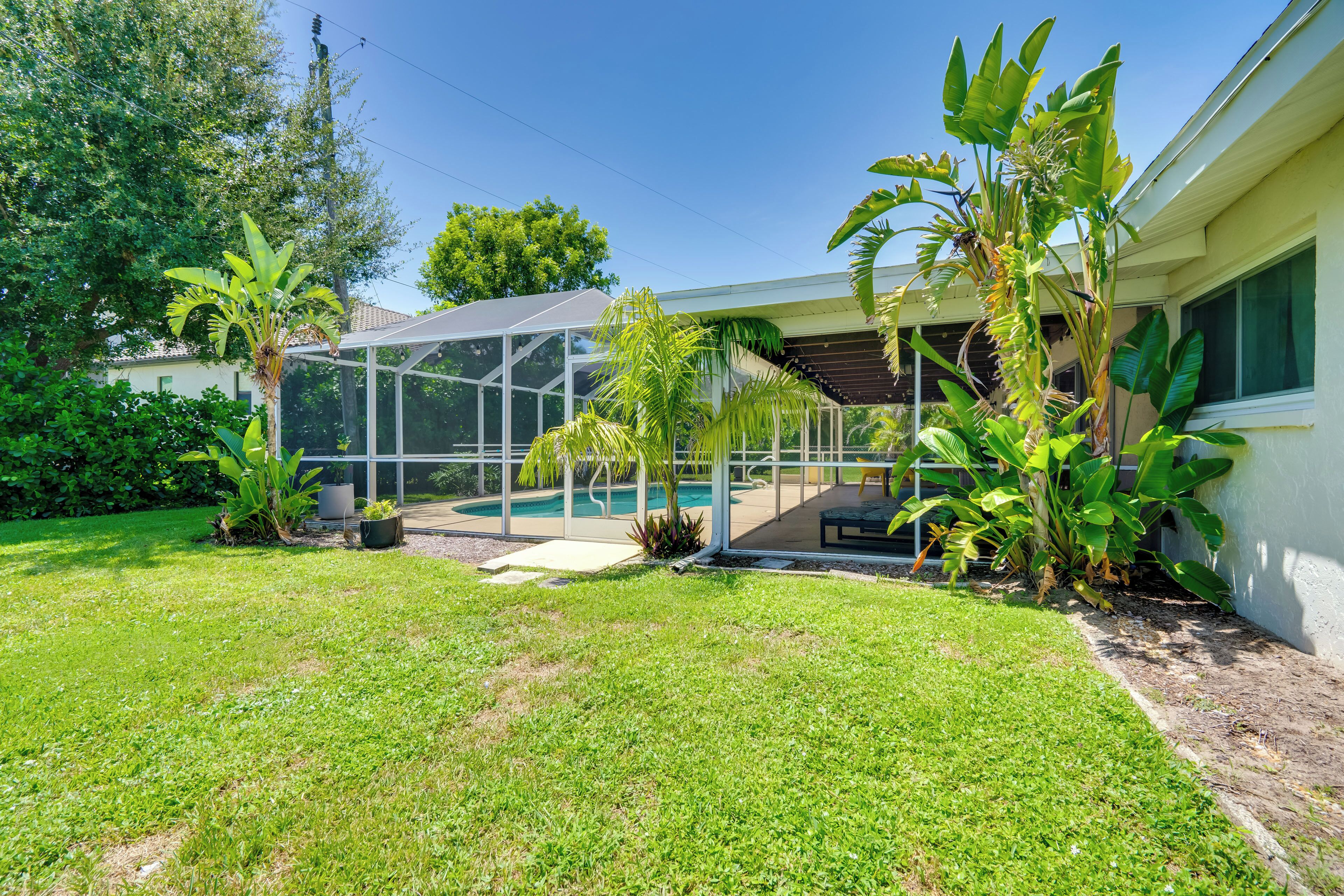 A house with a covered outdoor area, a pool, and various plants.