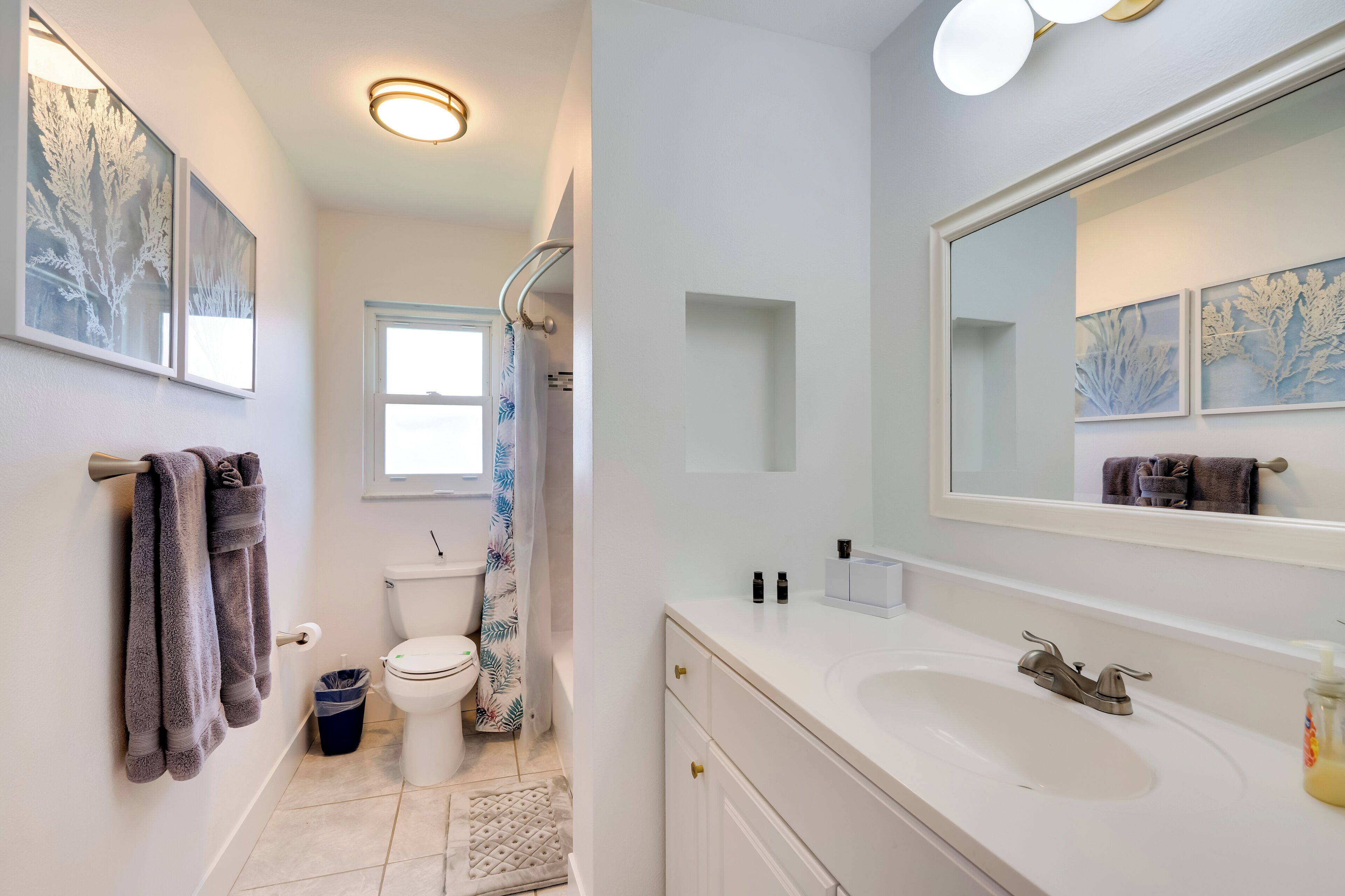 Een moderne badkamer met een witte wastafel, een grote spiegel en een douche.