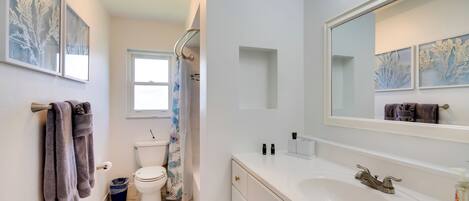 Een moderne badkamer met een witte wastafel, een grote spiegel en een douche.