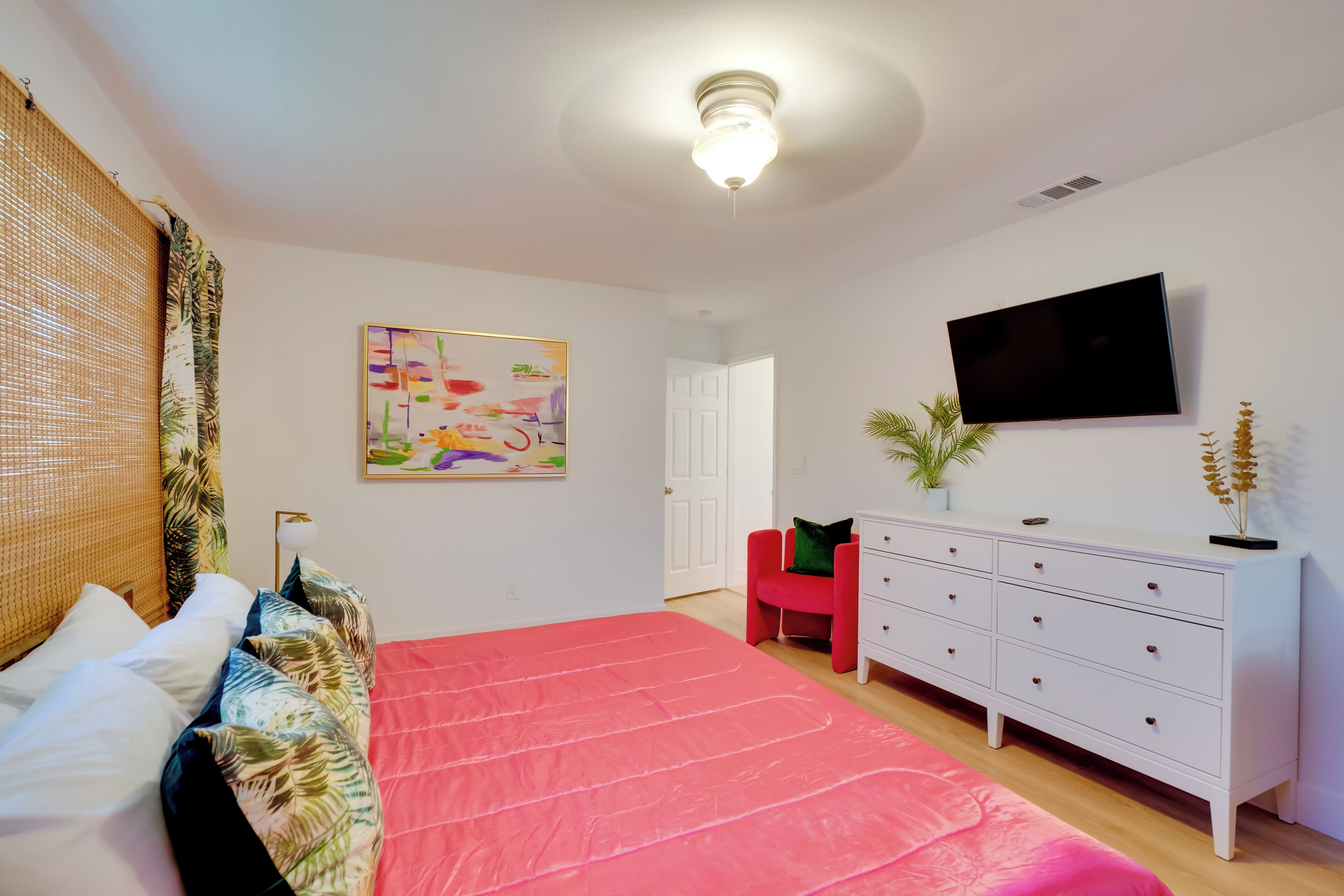 A bedroom with a bed, a TV, a dresser, and a door.